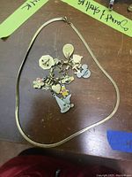 Full view of 18" gold chain and link charm bracelet with all charms laid on wood surface