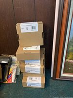 Stack of five unopened cardboard boxes containing Kidde combination smoke and carbon monoxide alarms, showing the back and side labels.
