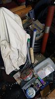 Photo showing white fishing vest or bibbers, metallic and wooden fishing accessories, and tackle boxes visible underneath