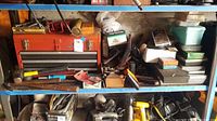 Shelf with assorted hand tools including hammers, wrenches, screwdrivers, saws, and metal files showing wear from use