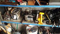 Shelf with various power tools including drills, jigsaw, circular saw, voltage meter and air compressor tank