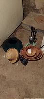 Overall lot photo showing camera, baskets, straw hat, and trumpet speaker on basement floor.
