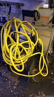 Craftsman welder partly visible with yellow extension cord coiled on top in a workshop setting.
