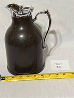 Side view of vintage bakelite thermos with chrome handle and lid, showing overall shape and size with measuring tape.
