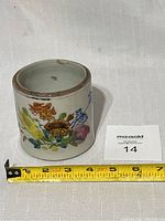 Overall view of the pottery jar with floral decoration and visible measuring tape showing about 3.5 inches tall