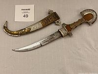Full view of the jambiya dagger with handle, sheath, and curved blade.