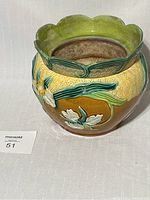 Front view of mid century modern earthenware flower pot with floral relief decoration and scalloped rim.