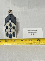 Front view of small blue and white porcelain house with KLM crown top and measuring tape showing size under 5 inches