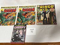 Four items laid out: two copies of 'The Valley of the Worm' comic book, one 'Ringo Kid' comic book, and one 'Best of Creepy' paperback.