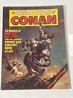 Front cover image of The Savage Sword of Conan #1 comic book showing Conan lifting an adversary with a nude woman in the background, includes promotional text and artist signature.