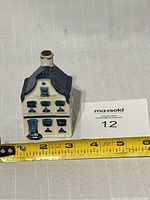 Front view of small ceramic house showing blue and white Delft style ornamentation with door and windows.