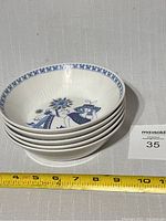 Stack of 5 white ceramic bowls decorated with a detailed illustration of a woman and floral motifs inside. A measuring tape shows the bowls' diameter is about 7.5 inches.