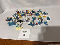 Wide shot of all 22 Smurf PVC figures arranged on a white cloth background showing variety of poses and characters.