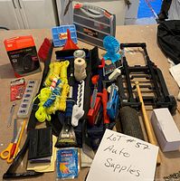 Photo showing assorted auto supplies including ropes, brushes, fan, tools, and organizational cases spread on a tabletop.