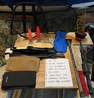 Image showing all car supplies including back support, ice scrapers, car jack, window screen, water hose scrubber, and two case logic car cases, with handwritten item list