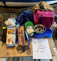 Photo shows all included items: pink pet carrier cage, two dog coats, two leashes, grooming tools, plush toy, food bowls with holder.