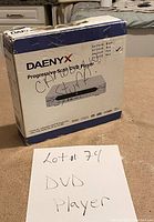 Box of Daenyx DV-2001B progressive scan DVD player with handwritten note indicating Lot #74 DVD player.