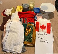 Photo showing assorted hand towels in various colors and patterns along with miscellaneous household items like plastic containers and candle.