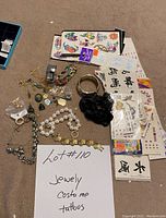 Photo showing assorted costume jewelry including bracelets, rings, and earrings, along with several sheets of temporary tattoos.