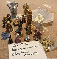 Photo of various porcelain statues, nativity figures, a Leaning Tower of Pisa replica, and Christmas ornaments arranged on the floor.