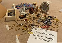 Wide angle photo showing all porcelain statues, costume jewelry, and accessories spread on the floor.