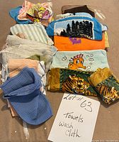 Photo of assorted towels and wash cloths stacked in two piles with various colorful patterns including animals and nature scenes.