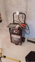 Full frontal view of the battery charger showing overall unit, handle and wheels