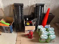 Overall view of black plastic car ramps, orange safety pylon, various car cleaning mitts and funnels, green jugs of washer fluid, and red hydraulic bottle jack on floor.