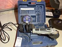 Photo of electric angle grinder and blue carrying case containing the grinder and multiple cut-off wheels.