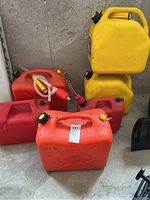 Photo of stacked yellow and red/orange jerry cans showing different sizes and spouts attached to some cans.