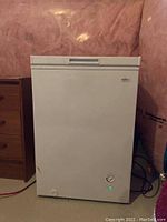 Front view of Koolatron chest freezer in basement with power light on.