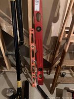 Photo showing two levels, one red and one orange, standing upright against basement wall near pipes and wooden beams.