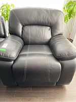 Front view of recliner in upright position showing black leather upholstery and contrast stitching