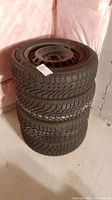 Stack of four winter tires with rims in basement setting