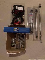 Lot overview with torque wrenches, socket set, and chargers on concrete floor