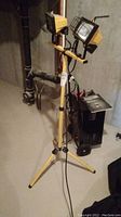 Full view of the Noma adjustable work light, yellow tripod stand with two lamps and wire guards, extension cord visible.