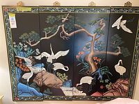Front view of four-panel folding screen depicting cranes, pine trees, rocks and flowers on black background