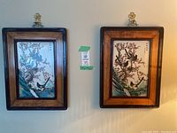 Two framed porcelain panels hanging side by side on wall