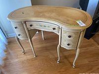 Full front view showing kidney-shaped desk with curved drawers, floral decor, and cabriole legs