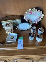 Assortment of vintage porcelain and ceramic decor items including ruffled bowl, spice jars, plates, and decorative tin.