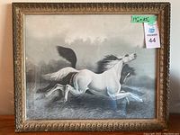 Full frontal view of the framed artwork depicting two wild horses in black and white, showing the ornate gold frame and overall condition.