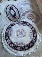 Four decorative area rugs arranged on carpeted floor showing floral designs and fringed edges