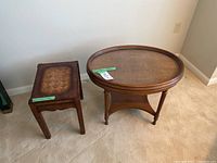 Front view of rectangular and oval wooden side tables on beige carpet near a white wall and electrical outlet.