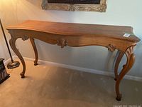 Full view of wooden carved sofa table with cabriole legs and carved apron