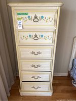 Front view of 6 drawer tall dresser with floral painted details and metal drawer handles.