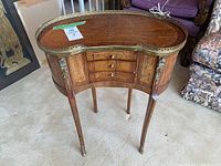 Front view of kidney-shaped occasional table showing gallery top and drawer configuration