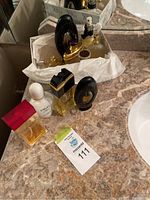 Photo of 11 perfume bottles displayed on a marble countertop, some in a white box lined with tissue paper, showing general contents of the lot and condition