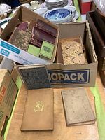 Boxes containing multiple antiquarian books showing wear and tear with various bindings and cover designs, including marbled, cloth, and leather.