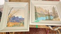 Two framed watercolour paintings side by side showing mountain and nature scenes, both signed by R.H. Davies.