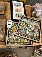 One photo showing four framed watercolor paintings, two stacked and two side by side, all depict figures with stylized faces and muted colors.